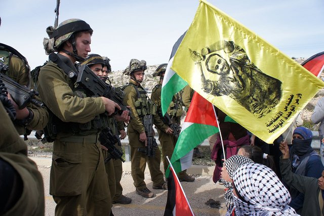 Israeli troops in the West Bank Palestinian town of Kafr ad-Dik. The yellow banner being waved at them in protest is a portrait of Marwan Barghouti the hunger strike leader